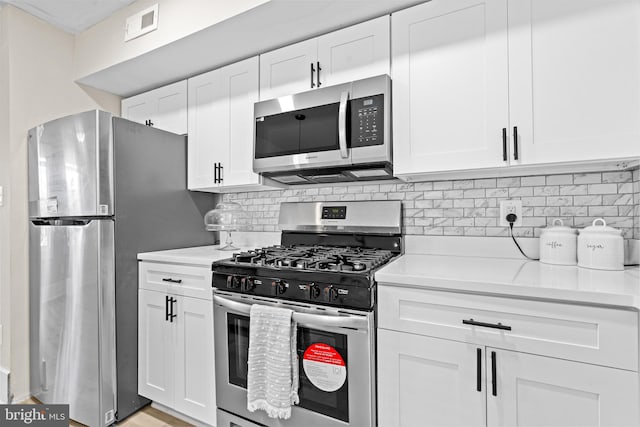 kitchen with backsplash, stainless steel appliances, light stone counters, and white cabinets