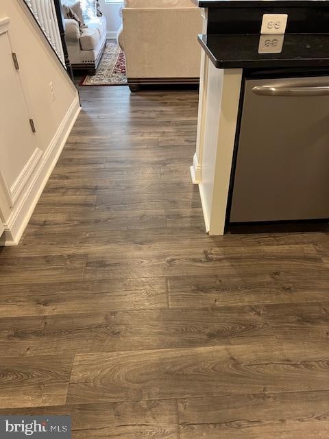 interior details featuring dark wood-type flooring, stainless steel dishwasher, and white cabinets