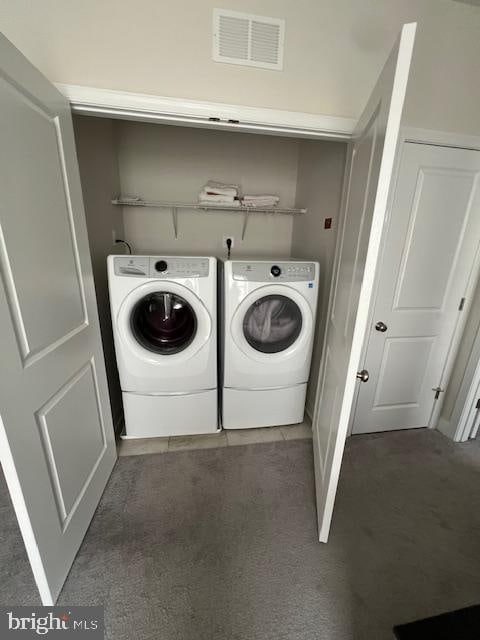 clothes washing area with washing machine and clothes dryer and dark colored carpet