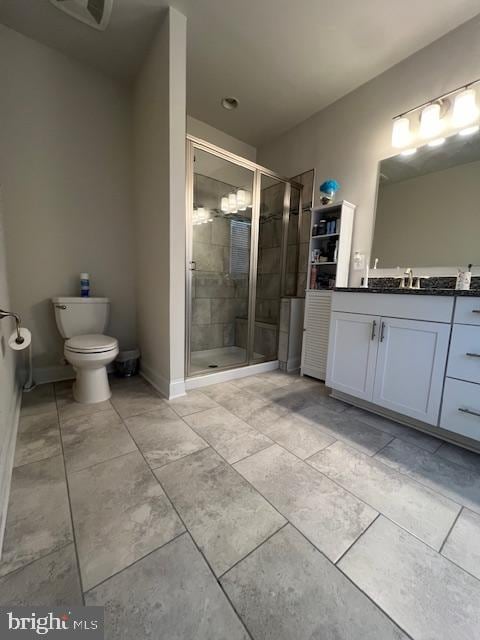 bathroom with vanity, a shower with shower door, and toilet