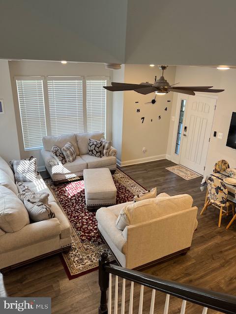 living room with a high ceiling, ceiling fan, and dark hardwood / wood-style flooring