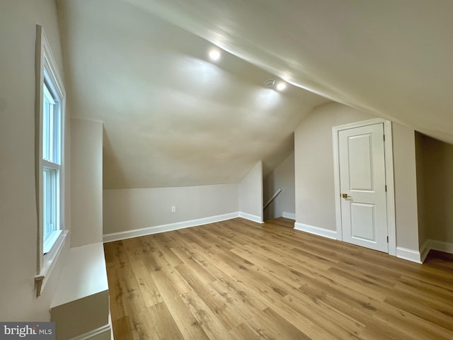 bonus room with a healthy amount of sunlight, light wood-type flooring, and vaulted ceiling