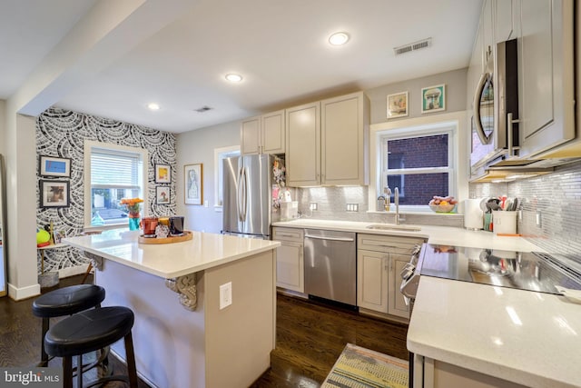 kitchen featuring sink, backsplash, a center island, stainless steel appliances, and dark wood-type flooring