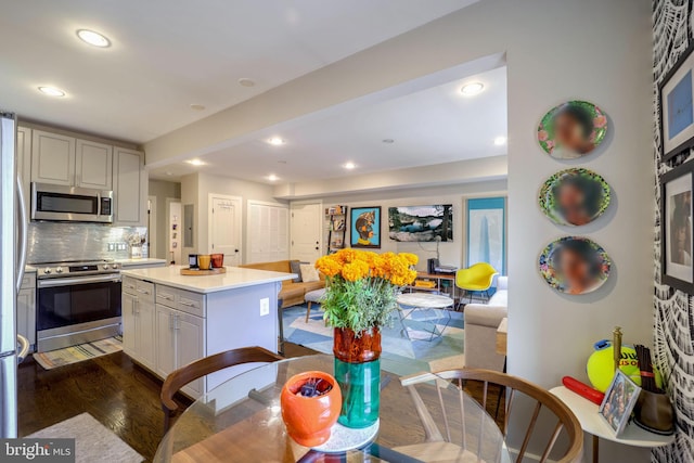 kitchen with backsplash, stainless steel appliances, dark hardwood / wood-style flooring, and a center island