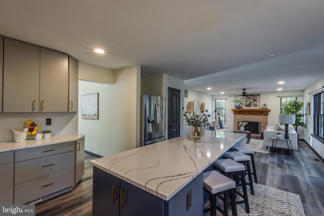 kitchen featuring a center island, dark wood-type flooring, a wealth of natural light, and stainless steel fridge with ice dispenser