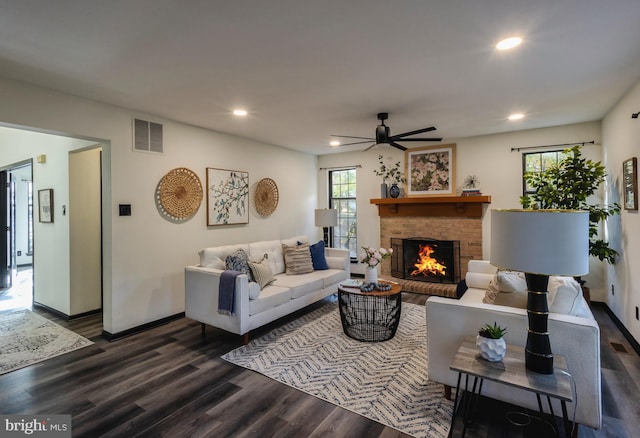 living room featuring ceiling fan, dark hardwood / wood-style flooring, and a fireplace