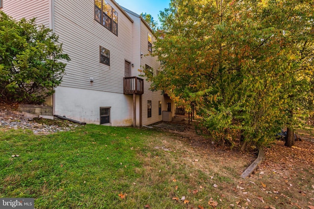 view of side of home with a lawn and a balcony