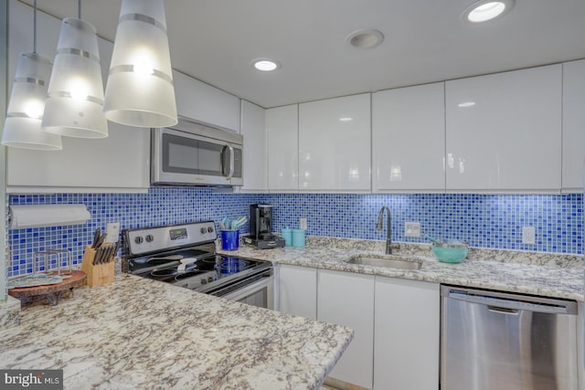 kitchen with white cabinets, pendant lighting, sink, and stainless steel appliances