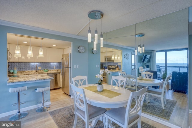 dining room with a textured ceiling, light hardwood / wood-style floors, and crown molding