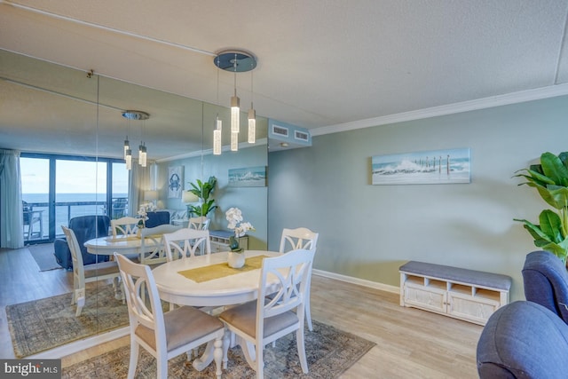 dining area with a textured ceiling, crown molding, hardwood / wood-style flooring, a water view, and a wall of windows