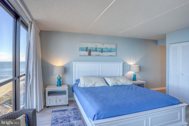 bedroom featuring hardwood / wood-style floors, a water view, a textured ceiling, and a closet