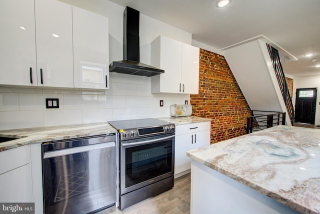 kitchen with wall chimney exhaust hood, white cabinetry, and stainless steel range with electric cooktop