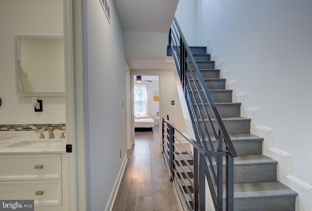 staircase with sink and wood-type flooring