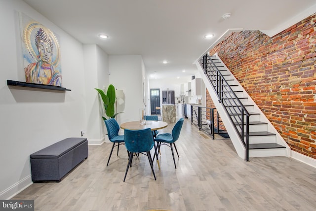 dining space featuring light hardwood / wood-style floors and brick wall