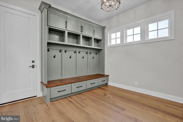 mudroom featuring light wood finished floors, baseboards, and an inviting chandelier