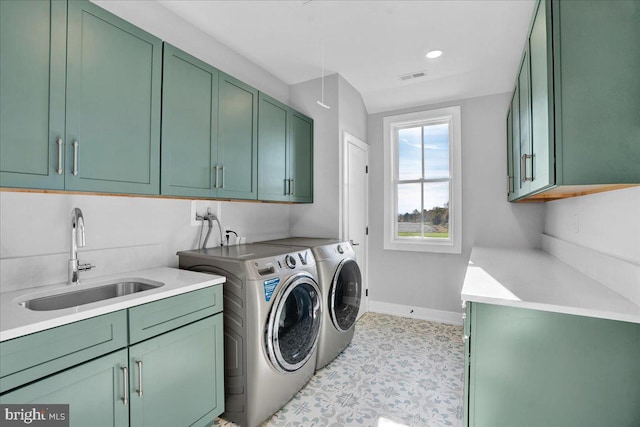 clothes washing area with washing machine and dryer, cabinets, and sink