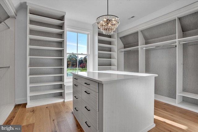 walk in closet with a chandelier and light hardwood / wood-style floors