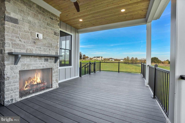 deck featuring an outdoor stone fireplace and ceiling fan