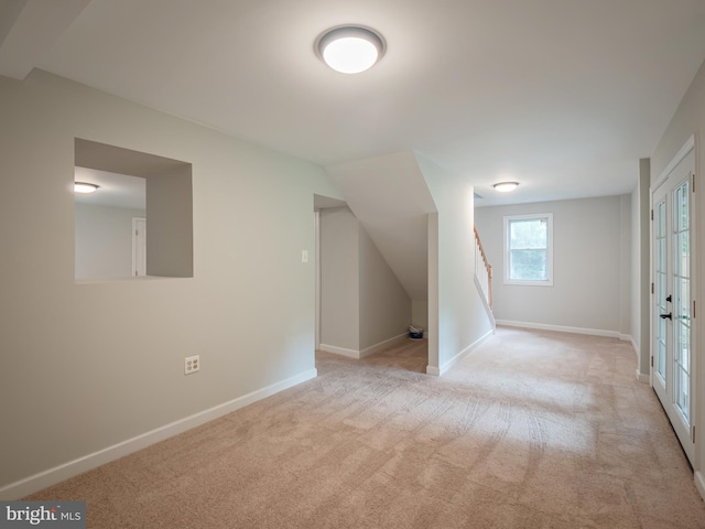 bonus room featuring french doors and light carpet