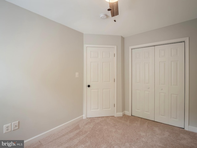 unfurnished bedroom featuring ceiling fan, light colored carpet, and a closet