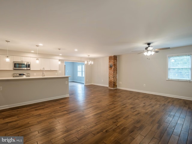 unfurnished living room with dark hardwood / wood-style flooring, sink, and ceiling fan with notable chandelier