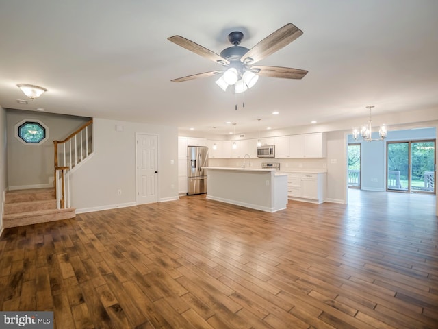 unfurnished living room with sink, ceiling fan with notable chandelier, and light hardwood / wood-style flooring