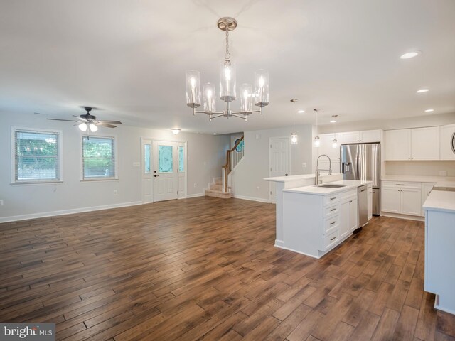 kitchen featuring sink, white cabinetry, hanging light fixtures, stainless steel appliances, and an island with sink