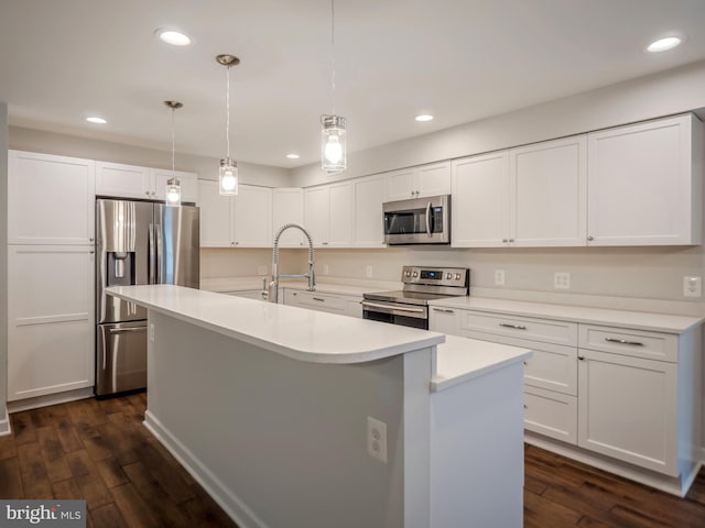 kitchen with white cabinetry, stainless steel appliances, decorative light fixtures, and a center island with sink