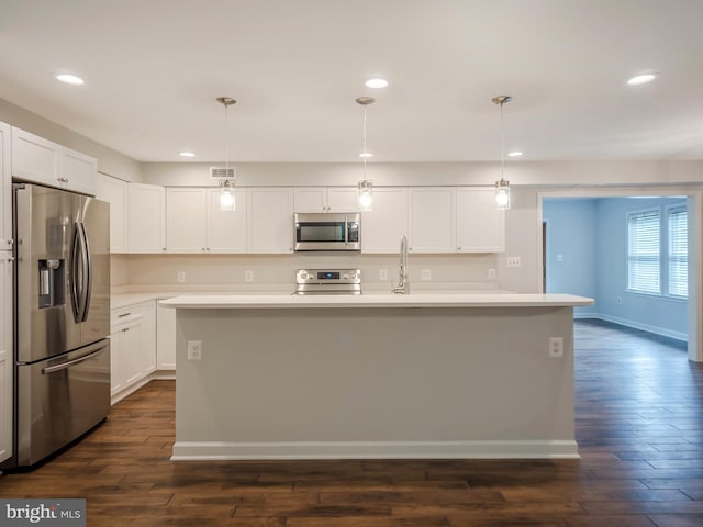 kitchen with white cabinetry, stainless steel appliances, an island with sink, and hanging light fixtures