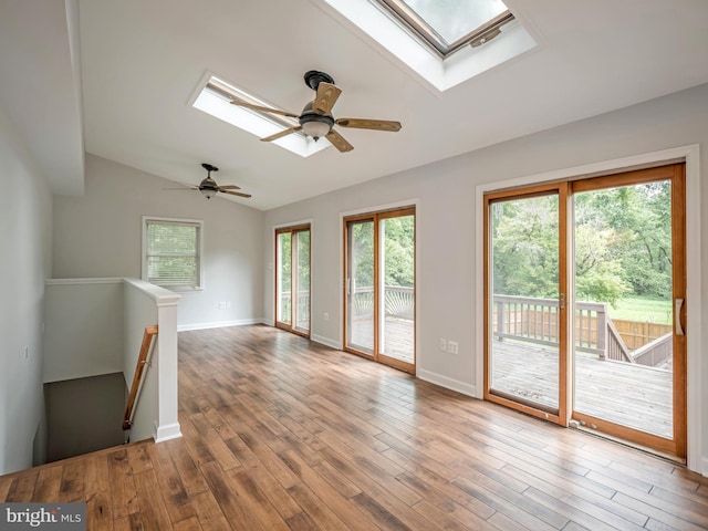 unfurnished living room with ceiling fan, wood-type flooring, and vaulted ceiling with skylight