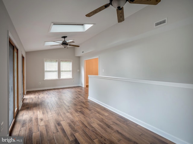 empty room featuring lofted ceiling with skylight, hardwood / wood-style floors, and ceiling fan