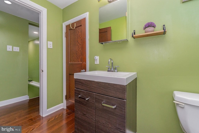 bathroom featuring toilet, hardwood / wood-style flooring, and vanity