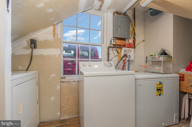 clothes washing area featuring washer and dryer, wood-type flooring, and electric panel