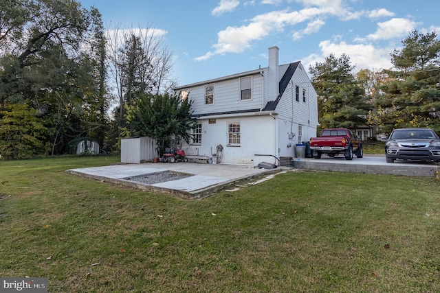 back of house featuring a storage shed, a yard, and a patio