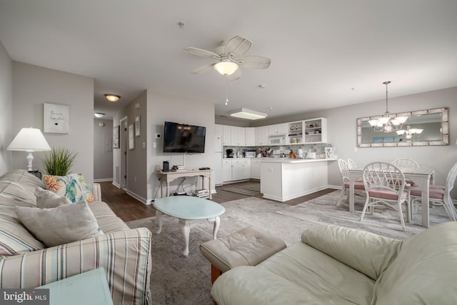 living room featuring ceiling fan with notable chandelier and dark hardwood / wood-style flooring