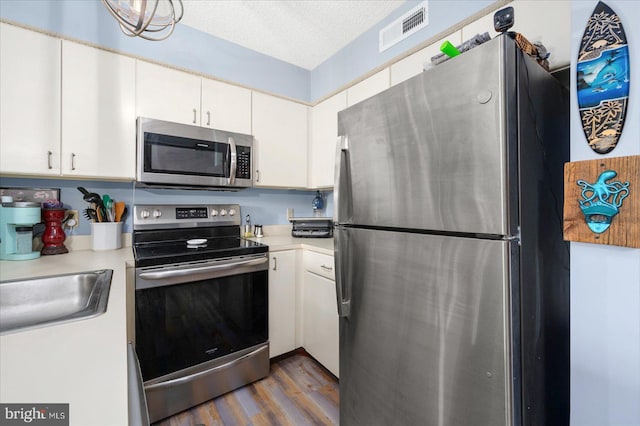 kitchen featuring appliances with stainless steel finishes, a textured ceiling, dark hardwood / wood-style floors, and white cabinetry