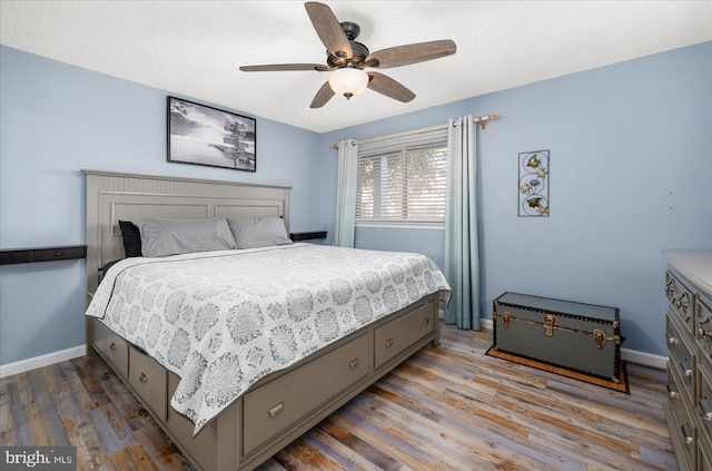 bedroom featuring ceiling fan, hardwood / wood-style flooring, and a textured ceiling