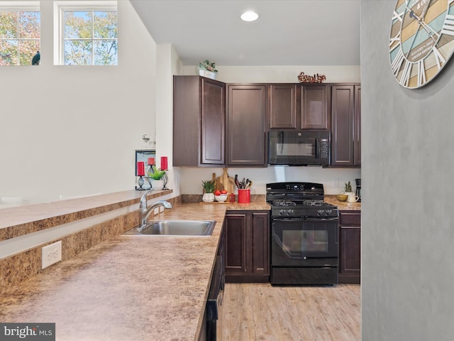 kitchen with dark brown cabinets, black appliances, sink, and light wood-type flooring