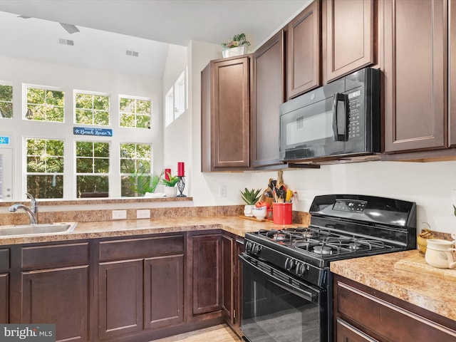 kitchen featuring sink, black appliances, dark brown cabinetry, and light wood-type flooring