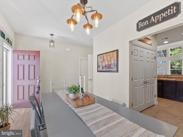 dining area with sink, light hardwood / wood-style flooring, and a chandelier