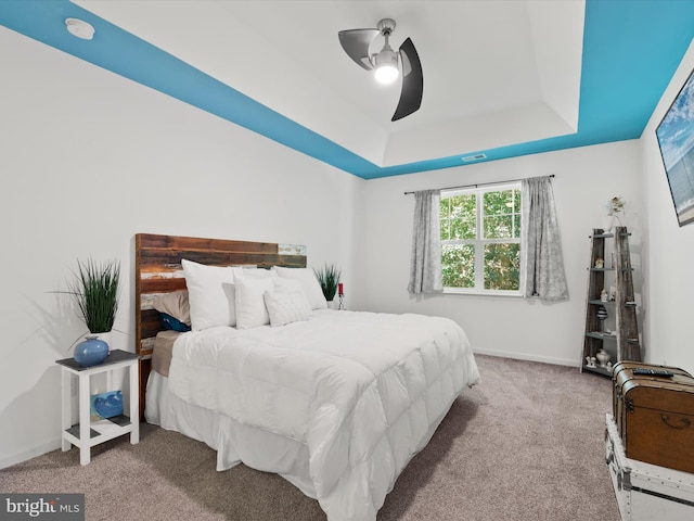 bedroom with light carpet, a tray ceiling, and ceiling fan