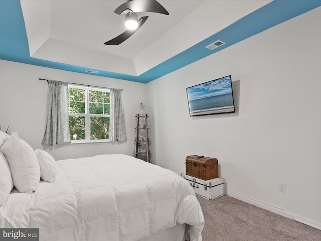 bedroom with light carpet, a tray ceiling, and ceiling fan