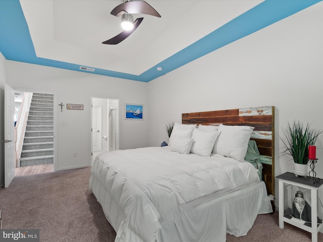 bedroom with ceiling fan, carpet, and a tray ceiling