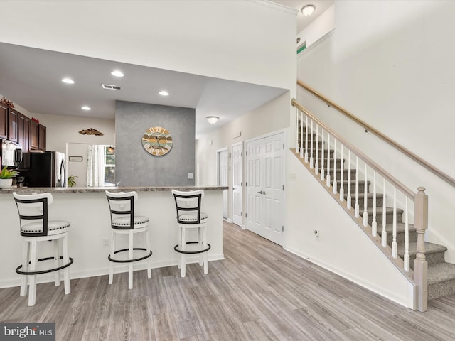 kitchen with light hardwood / wood-style flooring, kitchen peninsula, stainless steel appliances, and a breakfast bar area