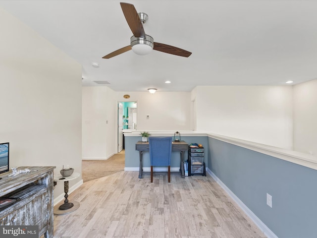 interior space featuring light hardwood / wood-style floors, a breakfast bar, kitchen peninsula, and ceiling fan