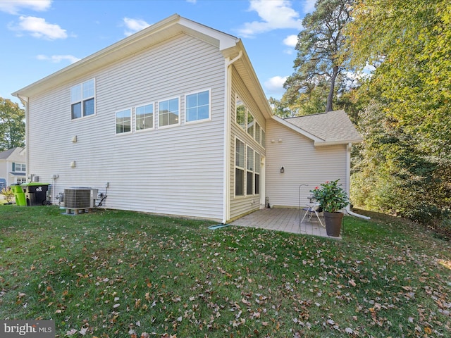 rear view of property featuring central AC and a lawn