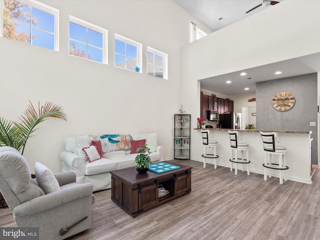 living room featuring a towering ceiling and light wood-type flooring