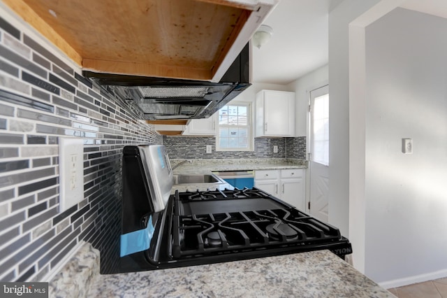 kitchen featuring sink, black range oven, white cabinets, and tasteful backsplash