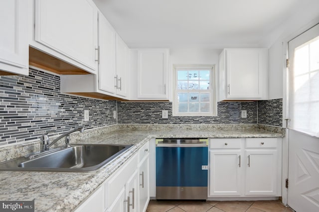 kitchen featuring stainless steel dishwasher, sink, white cabinets, and a healthy amount of sunlight