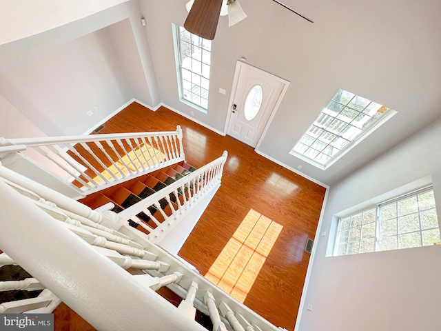 interior space featuring ceiling fan, wood-type flooring, and a high ceiling